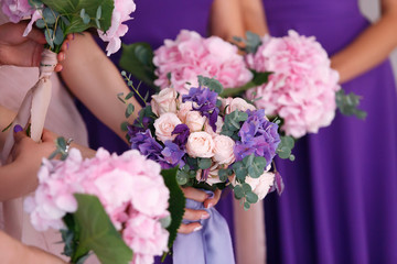 Obraz na płótnie Canvas the bride and bridesmaids in violet dresses with bouquets in hands. Morning of the bride, wedding day