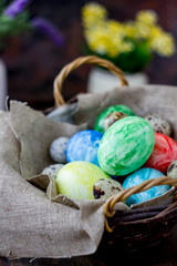 Colored easter eggs on basket over rustic table.
