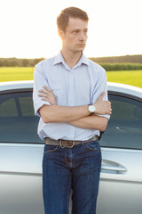 Young man looking away while standing by car at countryside