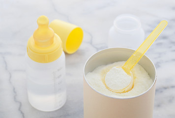 Milchpulver in einem Messlöffel Zubereitung von Babynahrung and Wasser in Flasche