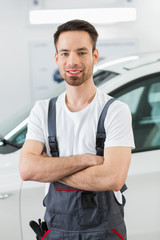 Portrait of confident maintenance engineer standing arms crossed in repair shop