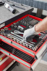 Cropped image of male mechanic taking tool from drawer in car workshop