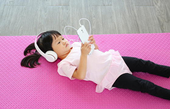 Cute little girl listening music with headphones and smartphone