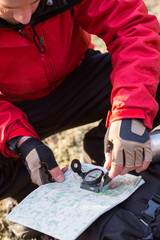 Male hiker using compass and map in forest