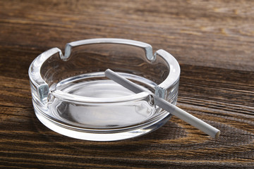 Thin cigarette in empty ashtray. White, long, thin cigarette.