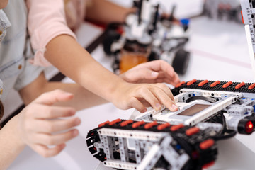 Skilled schoolchildren testing electronic robots at school