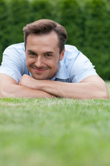 Portrait of smiling young man lying on grass in park