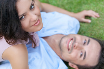 High angle portrait of playful young woman on top of man in park