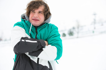Young man in jacket shivering in snow