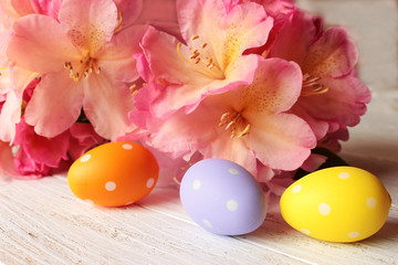 Rhododendron-Blüten mit Ostereiern auf weißem Holztisch, Frohe Ostern, Blumenstrauß