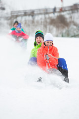 Fototapeta na wymiar Young couple enjoying sled ride on snow covered slope
