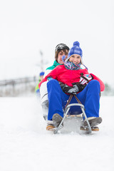 Fototapeta na wymiar Full length portrait of young couple enjoying sled ride in snow