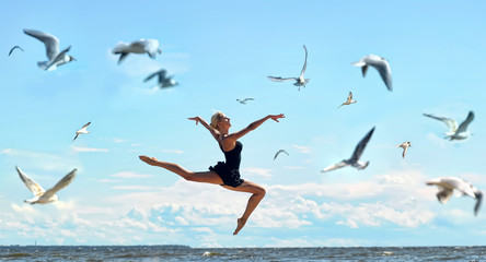 Fototapeta na wymiar Happy woman in black jumps on the seashore