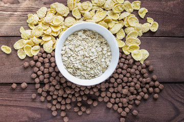 Bowl of dry oats with corn flakes  on wooden background