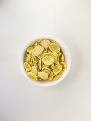 Bowl of yellow corn flakes with on white background
