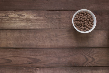 Bowl with cereal chocolate balls on a wooden table . Top view