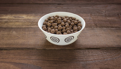 Bowl with chocolate balls on wooden table
