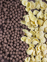 Cereal chocolate balls and corn flakes on wooden table can use for background