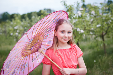  Cute little girl with bunch of lilac near apple trees in blossom at sunset. Kid enjoying happy childhood. Family, love, peace and happiness concept