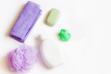 Obraz na płótnie Canvas Bath cosmetic flat lay photography/ Purple terry towel, sponge, baby soap, shampoo bottle and green toy rubber frog