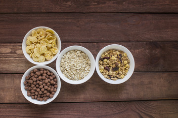 Different cereal breakfast in white bowl on wooden background