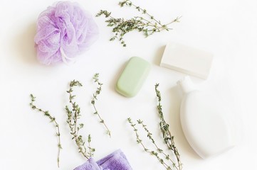 Flat lay bath products photography/ Purple sponge, green soap, shampoo bottle and herbs
