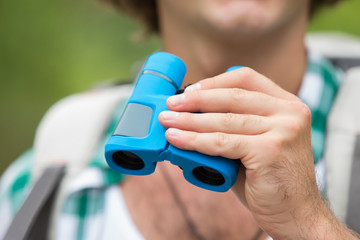 Close-up of male hiker holding binoculars