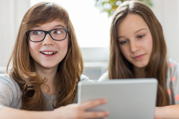 Happy girl with sister using digital tablet at home