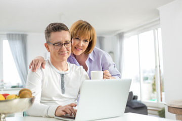 Loving couple using laptop together at home