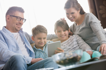 Happy family using digital tablet together in living room