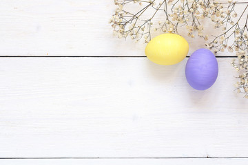 Easter eggs and white flowers on white  wooden background. Space for text.
