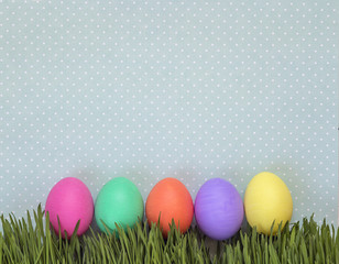 Easter eggs in fresh green grass on background in polka dots.