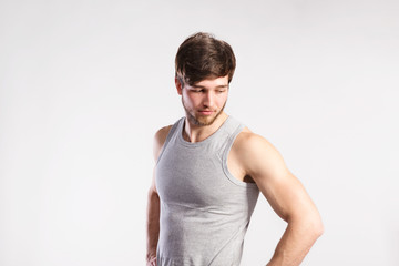 Handsome fitness man in gray tank top shirt, studio shot.