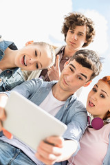 Young friends photographing themselves through digital tablet at university campus