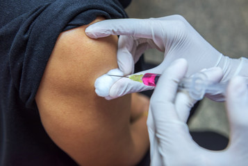 Close-up hands,nurses are vaccinations to patients using the syringe.Doctor vaccinating women in...