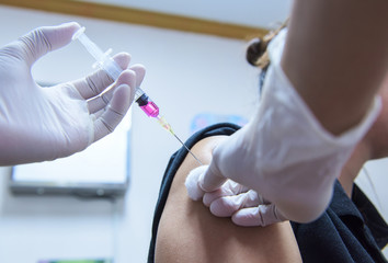 Close-up hands,nurses are vaccinations to patients using the syringe.Doctor vaccinating women in hospital.Are treated by the use of sterile injectable upper arm. injection