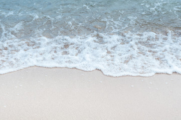Wave with foam on the sandy beach