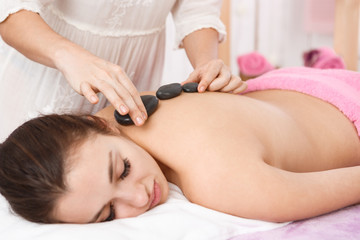 Obraz na płótnie Canvas Masseur doing massage with hot stones on woman back 