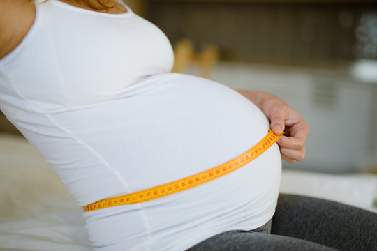 Pregnant Woman Measuring Belly With Metetr