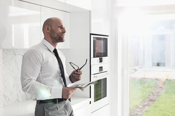 Thoughtful businessman holding newspaper at home