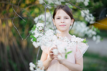 Adorable little girl in blooming apple tree garden. Cute child near apple tree at spring.