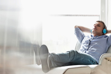 Full-length of relaxed Middle-aged man listening to music at home