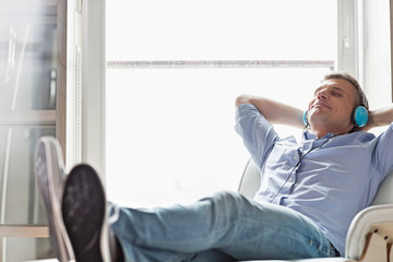 Full-length of relaxed Middle-aged man listening to music at home