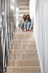 Full-length of sisters listening to music on stairway