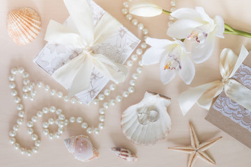 Fototapeta na wymiar Present, beads, seashells, orchid and rings on wooden background