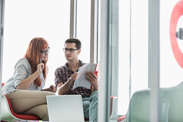 Business colleagues reading file in creative office