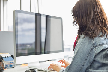 Rear view of businesswoman using desktop computer in creative office