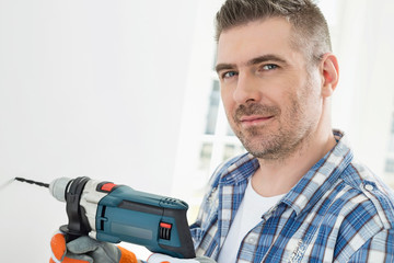 Portrait of mid-adult man drilling hole in wall