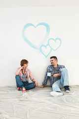 Full-length of mid-adult couple with painted hearts on wall