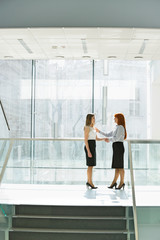 Full-length of businesswomen shaking hands at office hallway